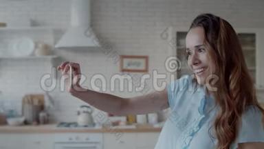 快乐的女人在现代厨房自拍照片。 女孩摆姿势拍照。